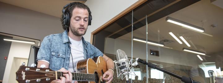 A student plays his guitar in a Sweetwater recording studio